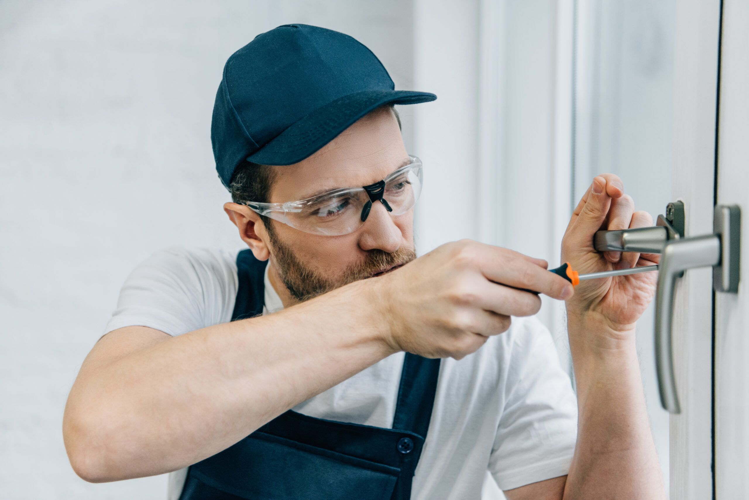 craftsman in goggles fixing window handle with screwdriver